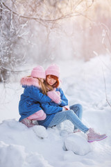 Pretty Daughter Hugs Her Mom In The Winter Forest