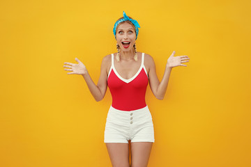 Wow! Shock! Expressing joy! Happy pretty young woman in shorts. Yellow wall background.