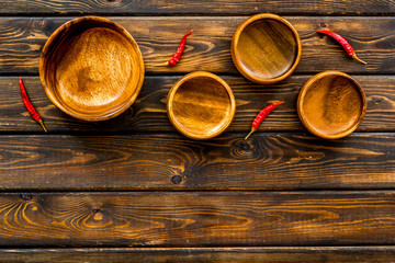 Asian cuisine concept. Wooden bowls and chili pepper on dark wooden background top view copy space