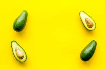 Avocado pattern - halfs of fruit - on yellow background top view copy space