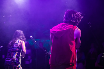 woman and man are singing and on the stage, male and female two singers performing during live music performance, from the back view