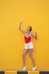 Fototapeta na wymiar Joy and music. Summer vacation. Colorful studio portrait of happy young woman with earphones is dancing and singing.