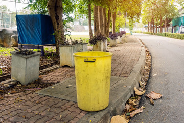 Fototapeta premium An old yellow dustbin in the public park beside the walk way for protect environment.