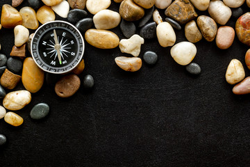 Sea journey, travelling and vacation concept. Compass on rocks and black background top view copy space