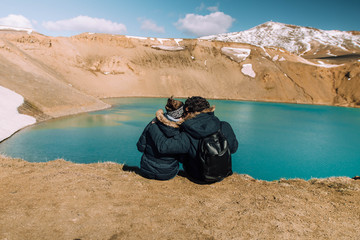 Couple sitting on the edge of the Krafla caldera in Myvatn, Iceland