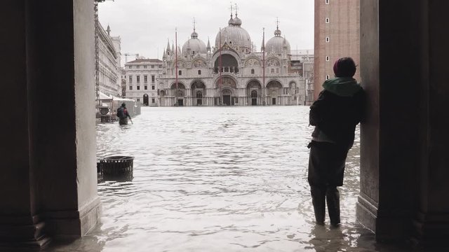 Female tourist standing under an arch contemplating the flood in st mark&rsquo;s square, Venice. 4k