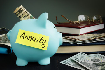 Annuity written on yellow sheet and piggy bank with money. - obrazy, fototapety, plakaty