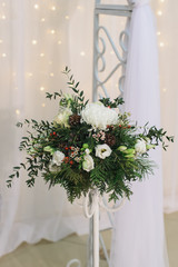 marriage flower arrangement with chrysanthemum, pine branches and cones, eustoma, ilex, thuja, waxflover, Eucalyptus parvifolia, freesia on high stand on floor for winter wedding indoors, stock photo