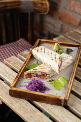 Grilled roll shawarma with chicken breast, tomatoes and red cabbage served on wooden tray