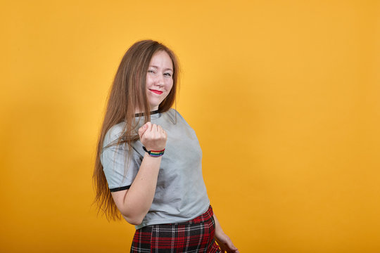 Young caucasian lady wearing gray shirt looking so funny, over white wall happy and pointing to the side, keeping fist up