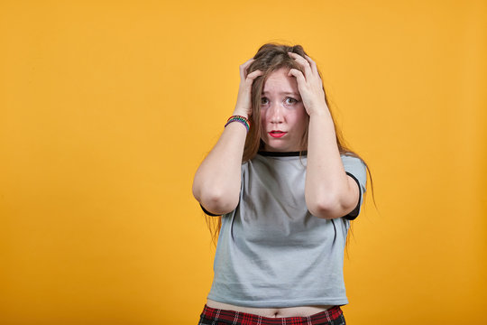 Relaxed young woman in casual clothes keeping eyes opened, with hands behind head isolated on orange wall background in studio. People sincere emotions, lifestyle concept.