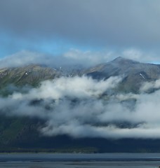 Fototapeta na wymiar Hazy Day Clouds Hang Over The Water Front Partially Hiding Alaska Mountains. 