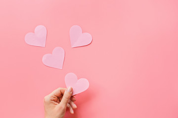 Valentine's day background. Female hands holding pink hearth. Flat lay, top view, mockup, template,...