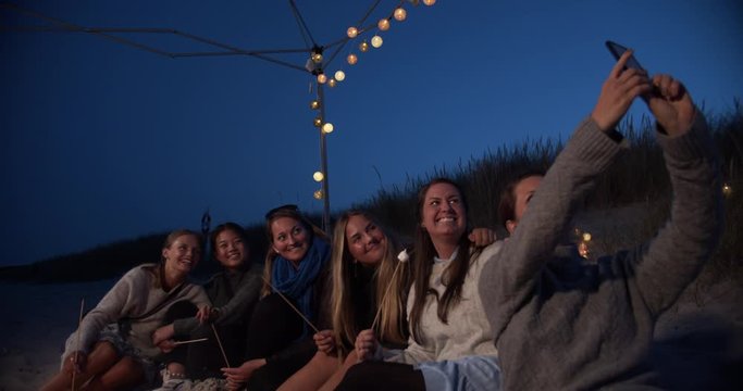 Girlfriends having a good time around campfire on the beach. Cinematic lifestyle scene perfect for travel or corporate video projects.