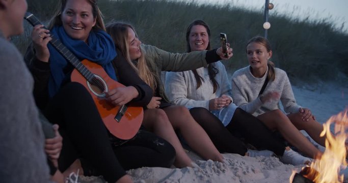 Girlfriends having a good time around campfire on the beach. Cinematic lifestyle scene perfect for travel or corporate video projects.
