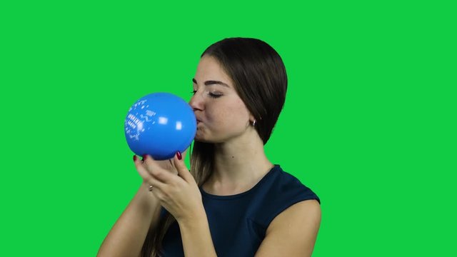 Girl blowing up a balloon in front of a green screen