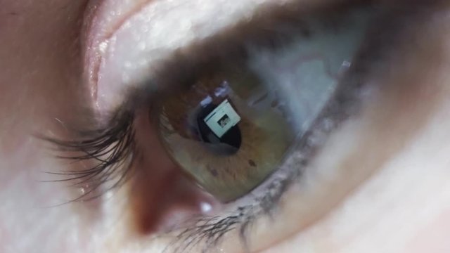 Extreme close up, womans eye reflecting social media feed on laptop screen