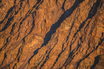 Sunny nature background of rockies in sunlight. Vivid natural mountain texture of big rough rocks. Full frame of bright giant craggy surface. Rocky mountain close-up. Plane of shiny rocks on sunset.