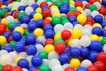 Fototapeta na wymiar Pool with bright colorful plastic balls on kids playground. White, blue, yellow, red, green balls. Entertainment toys for happy children.