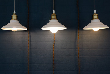 Obraz premium Turned on hanging lamp on a dark wall background.