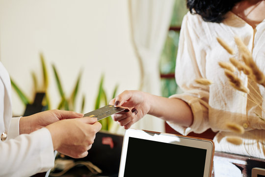 Cropped image of female hotel guest paying for service at reception with credit card