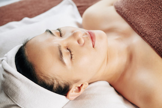 Beautiful young Asian woman with lying in bed in spa salon after relaxing beauty treatment