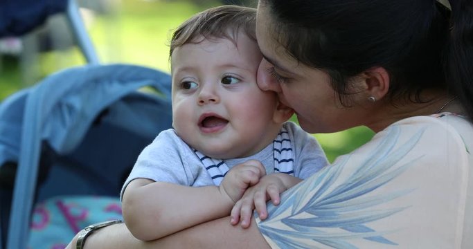 Mother whispering something in baby toddler infant son in ear