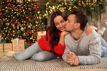 Happy young couple lying on floor in living room decorated for Christmas