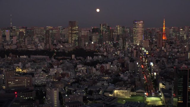 TOKYO, JAPAN - NOVEMBER 2019 : Aerial high angle view of cityscape of TOKYO at night. Scenery of central downtown area and business district. Full moon in the sky.