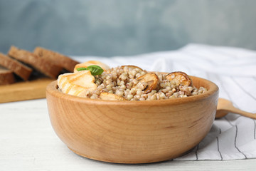 Tasty buckwheat porridge with meat on white wooden table