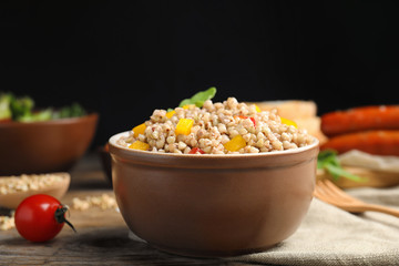 Tasty buckwheat porridge with vegetables on wooden table