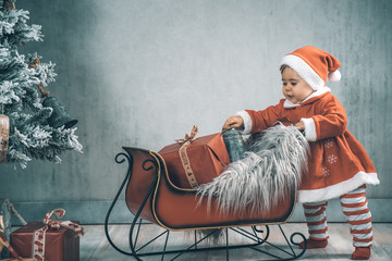 Weihnachtsszene Baby Kind im Santa Claus Dress roter Schlitten Geschenke Christbaum Xmas retro - Var. 3