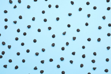 Delicious dark chocolate chips on light blue background, top view