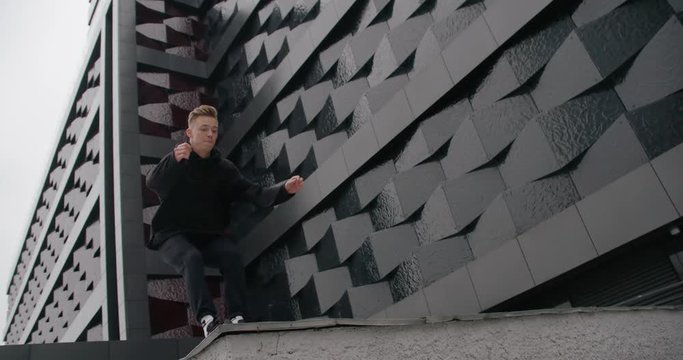 Young man does flip, parkour on modern city, free running in slow motion.