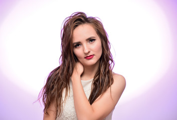 Fototapeta premium The concept of beauty, fashion, makeup, cosmetics. Portrait of a pleasant young pretty brunette girl with a beautiful hairstyle, great makeup, long curly hair on a colorful background.