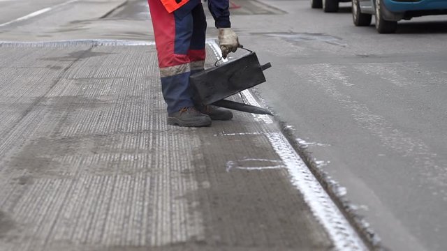 Road repair. Work details, workers pour resin road surface to cover the asphalt. Men in specialized clothing repair asphalt in the city. Preparation of asphalt pavement for laying new asphalt.