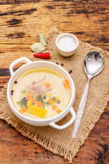 Transparent duck broth in bowl with vegetables. Traditional bouillon, healthy meal. Old wooden background