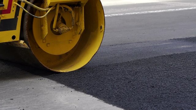 Close-up of an asphalt rink lays new asphalt on the road. Repair of roads. The repair work of industrial machines in the city.