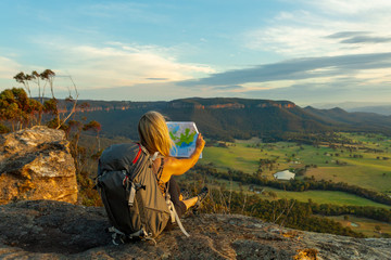 Hiker or tourist sitting on a rock using a map