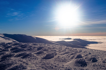 Clouds below the mountain, visible mountain range above the clouds, winter, sunset