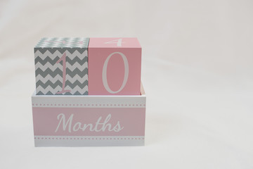 Rosa grauer Monatswürfel 10 Monate 10 months vor weißem Hintergrund