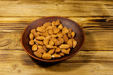 Almonds in ceramic plate on a rustic wooden table
