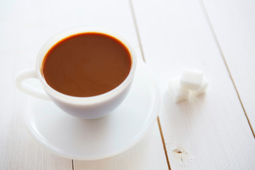 White coffee cup with rich coffee on a white wooden table