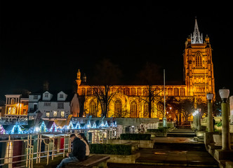 The Church of St Peter Mancroft illuminated by bright spot lights and the market place in the city of Norwich captured at night