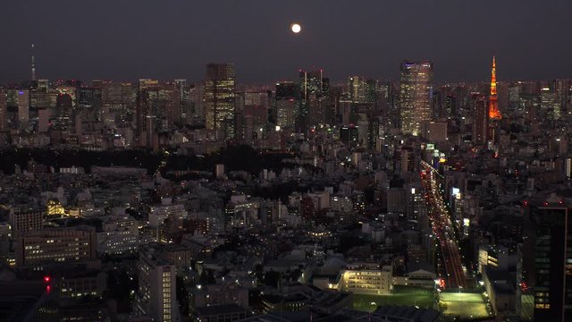 TOKYO, JAPAN - NOVEMBER 2019 : Aerial high angle view of cityscape of TOKYO at night. Scenery of central downtown area and business district. Full moon in the sky.