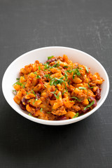 Homemade Chili Mac and Cheese in a white bowl over black surface, side view. Close-up.