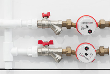 Water pipes with water meters on white wall background. Pipeline background.