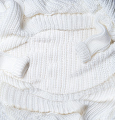 Background of white knitted blanket with sweater sleeves . Top view. Flat lay. Cold weather season layout.  Insta style. Modern