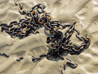 Old rusty chain in the sand. Close-up view.