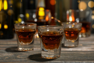 Whiskey shots on wooden bottled table, close up